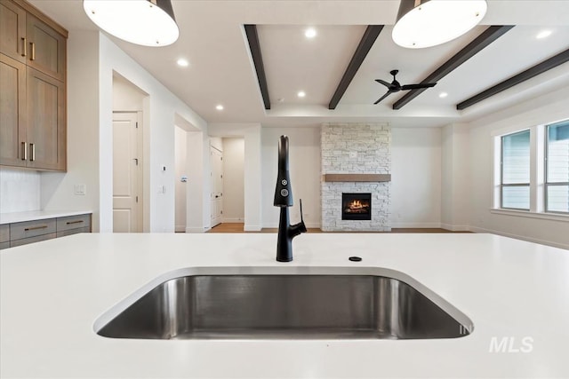 kitchen with beam ceiling, light countertops, a sink, and open floor plan