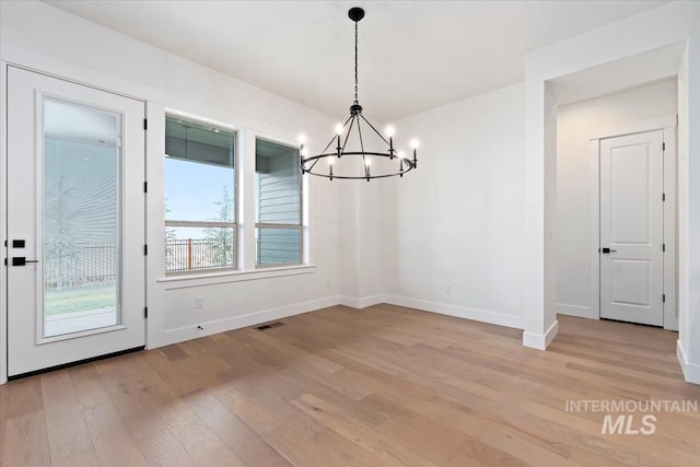 unfurnished dining area with a chandelier, light wood finished floors, visible vents, and baseboards