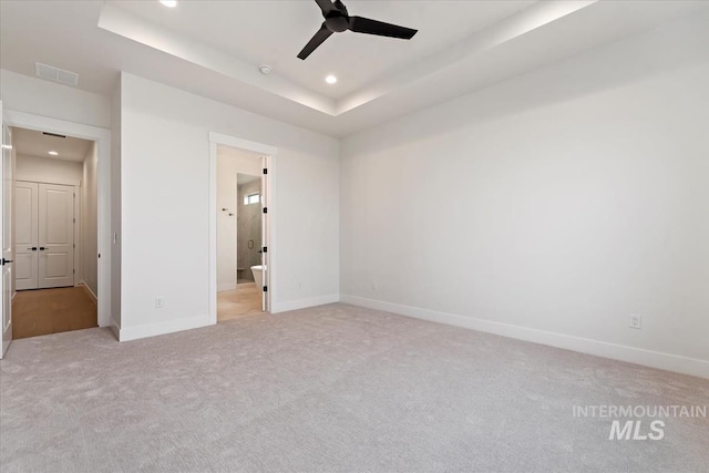 unfurnished bedroom featuring a tray ceiling, baseboards, and recessed lighting