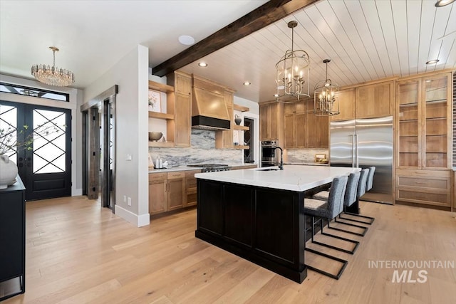 kitchen featuring stainless steel appliances, an inviting chandelier, open shelves, premium range hood, and light wood-type flooring