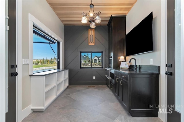interior space with an inviting chandelier, wooden ceiling, baseboards, and a sink