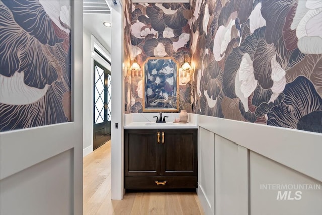 bathroom with baseboards, vanity, wood finished floors, and recessed lighting