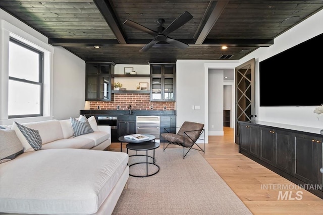living area with wooden ceiling, beam ceiling, light wood-style floors, and ceiling fan