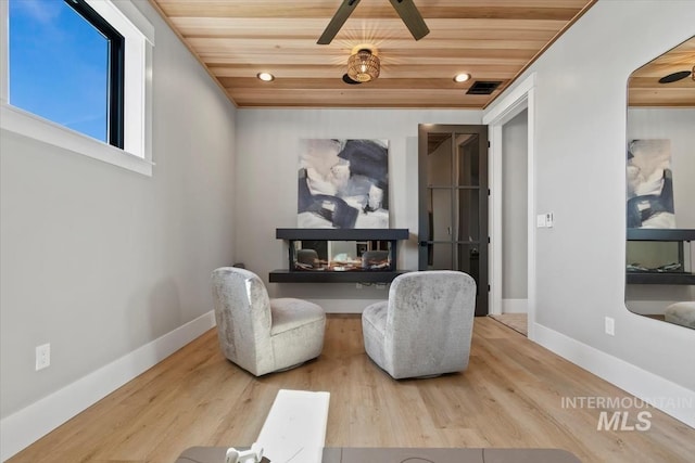 sitting room with wood ceiling, wood finished floors, visible vents, and ceiling fan
