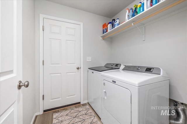 laundry room featuring washing machine and dryer, light wood-type flooring, and baseboards