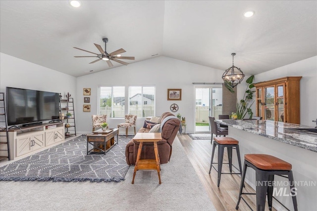 living area featuring vaulted ceiling, light wood-type flooring, a ceiling fan, a chandelier, and recessed lighting