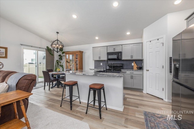 kitchen with black microwave, stainless steel fridge, a sink, gray cabinetry, and a chandelier