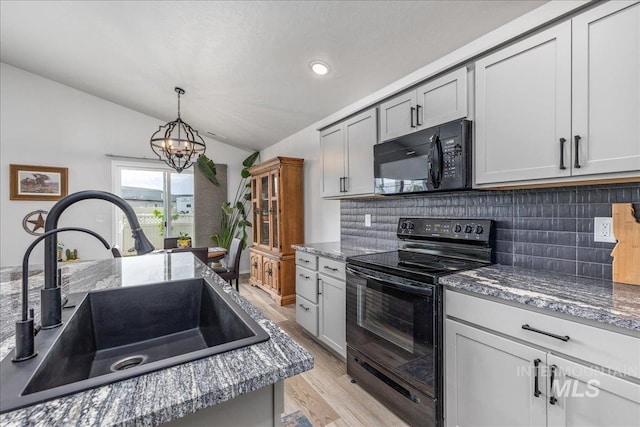 kitchen with black appliances, a sink, vaulted ceiling, backsplash, and light wood-style floors