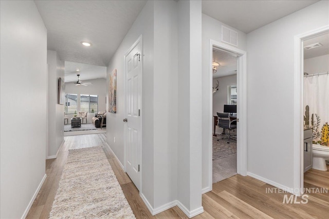 corridor with a desk, light wood finished floors, baseboards, and recessed lighting