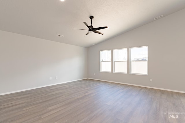 empty room featuring visible vents, ceiling fan, lofted ceiling, and wood finished floors