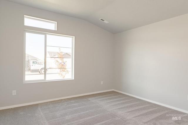 spare room with visible vents, baseboards, lofted ceiling, and carpet floors