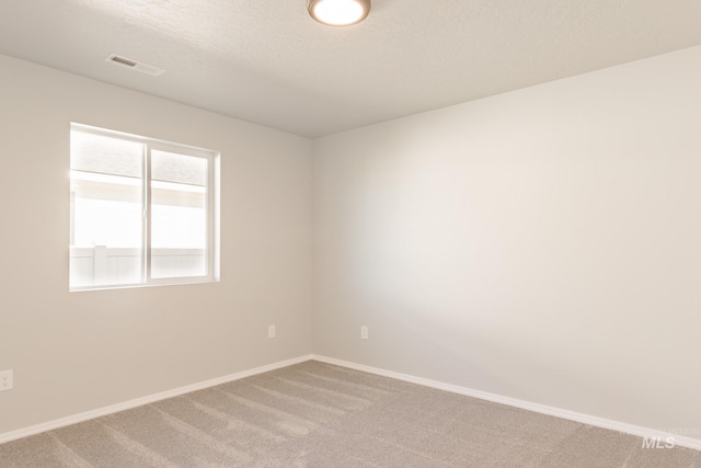 unfurnished room featuring visible vents, light carpet, a textured ceiling, and baseboards