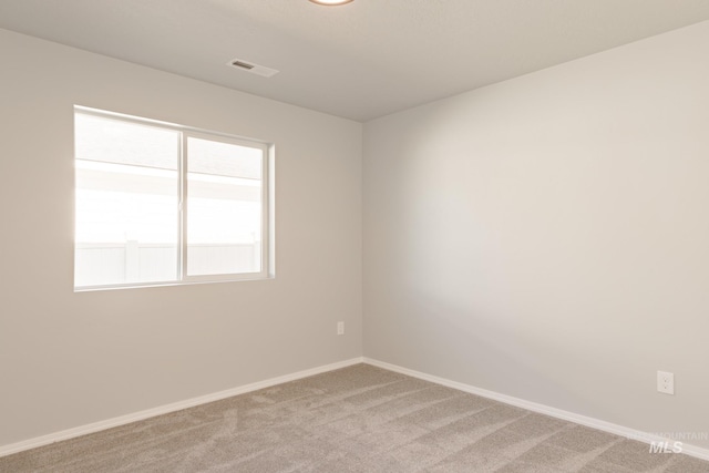 spare room featuring visible vents, baseboards, and light colored carpet