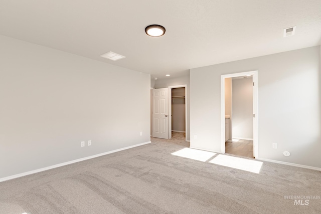 unfurnished bedroom with a spacious closet, carpet, visible vents, and baseboards