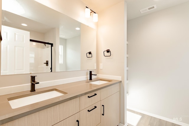 bathroom featuring double vanity, a shower, visible vents, and a sink