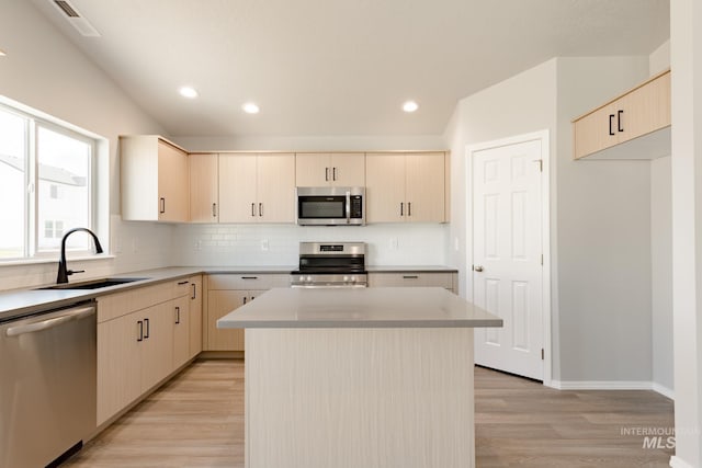 kitchen featuring tasteful backsplash, appliances with stainless steel finishes, light wood-type flooring, and a sink