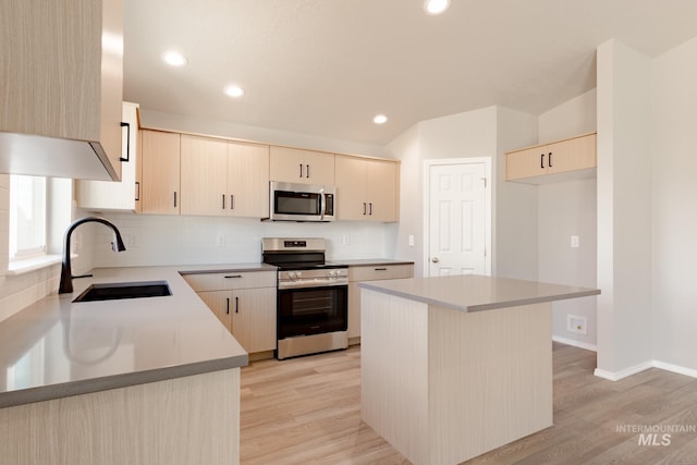 kitchen with a sink, decorative backsplash, appliances with stainless steel finishes, and light wood finished floors