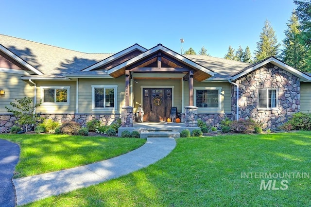 3801 S Carpenter Loop, Post Falls, ID 83854 - craftsman-style house featuring a porch, a front yard, a shingled roof, and stone siding