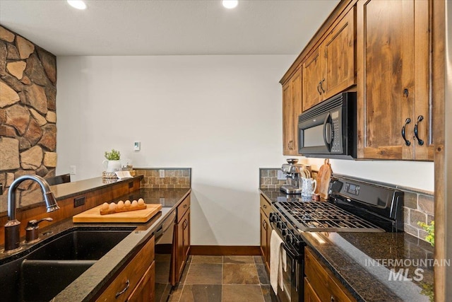3801 S Carpenter Loop, Post Falls, ID 83854 - kitchen featuring brown cabinetry, a sink, baseboards, black appliances, and dark stone countertops