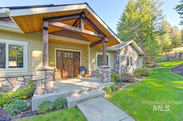 3801 S Carpenter Loop, Post Falls, ID 83854 - view of exterior entry with a porch, a yard, and stone siding