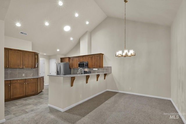 2870 N Cloverdale, Boise, ID 83713 - kitchen featuring appliances with stainless steel finishes, a peninsula, a kitchen breakfast bar, brown cabinetry, and recessed lighting