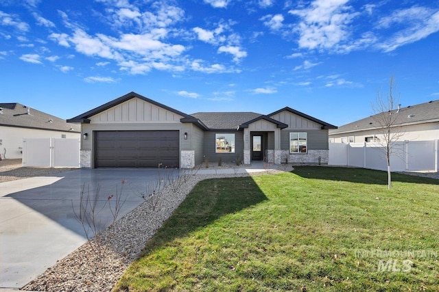 view of front of house featuring board and batten siding, fence, concrete driveway, a front yard, and a garage