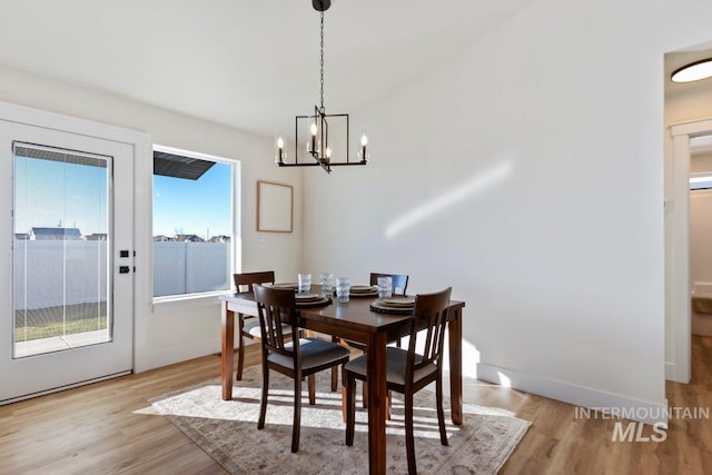 dining area featuring light wood-style flooring, baseboards, and an inviting chandelier