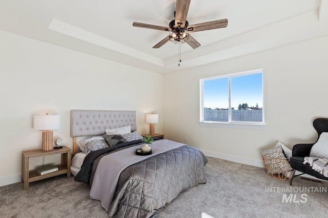 bedroom featuring a tray ceiling, carpet flooring, baseboards, and ceiling fan