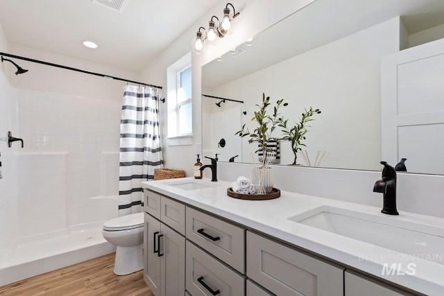 full bath with a shower with curtain, wood finished floors, and a sink