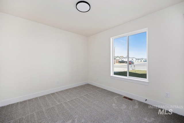 carpeted empty room featuring baseboards and visible vents