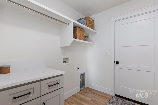 clothes washing area with baseboards, light wood finished floors, hookup for an electric dryer, laundry area, and washer hookup