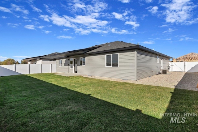 back of property with central AC, a lawn, a fenced backyard, a patio area, and a gate