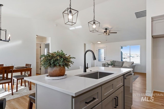 kitchen with visible vents, ceiling fan with notable chandelier, a sink, stainless steel dishwasher, and light countertops