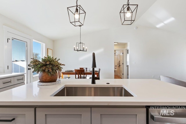 kitchen featuring dishwasher, lofted ceiling, light countertops, and a sink