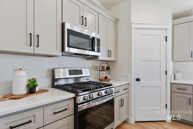 kitchen with light countertops, gray cabinets, light wood finished floors, and stainless steel appliances