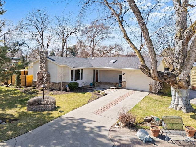 view of front of home featuring stone siding, a garage, driveway, and a front lawn