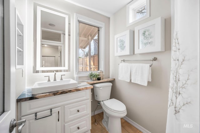 bathroom with plenty of natural light, toilet, vanity, and baseboards