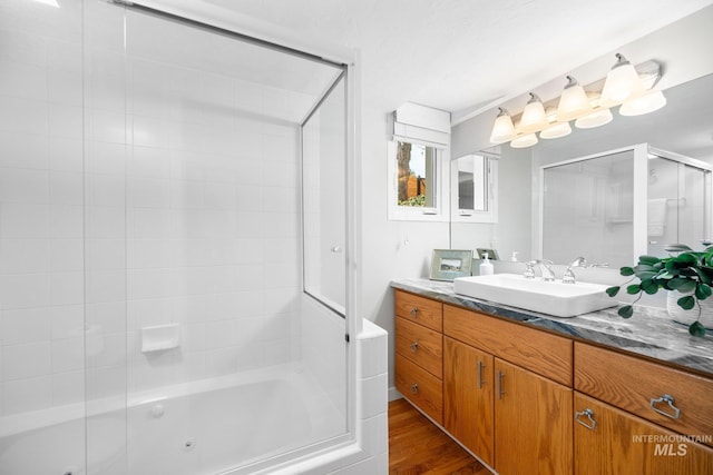 full bath with wood finished floors, vanity, and a combined bath / shower with jetted tub