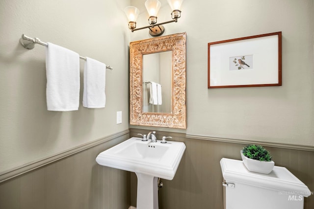 half bath featuring toilet and wainscoting