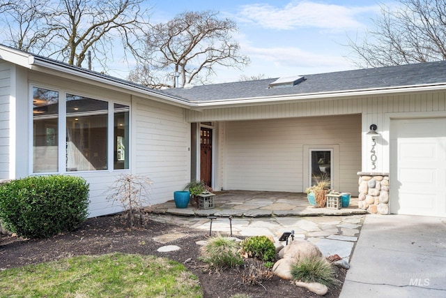 view of exterior entry featuring a shingled roof and a garage