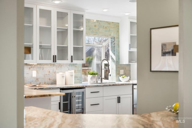 bar with a sink, tasteful backsplash, and beverage cooler