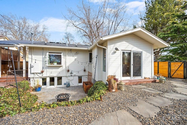 rear view of property with a gate, a patio area, fence, and a fire pit