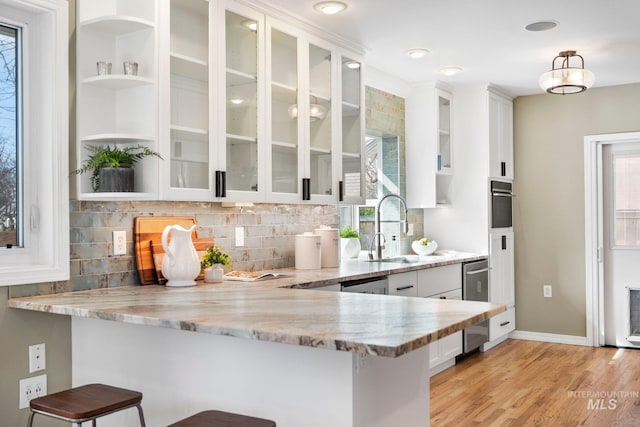 kitchen featuring white cabinetry, plenty of natural light, light stone countertops, and a kitchen bar