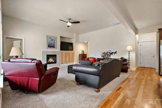 living room with ceiling fan, a fireplace, visible vents, and light wood-style flooring