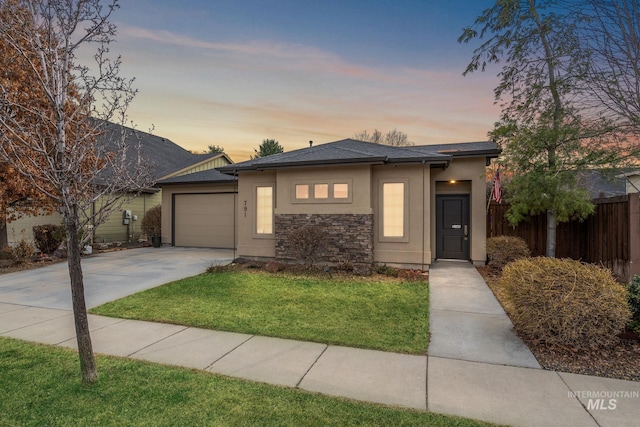 view of front of home featuring a garage, concrete driveway, stone siding, fence, and stucco siding