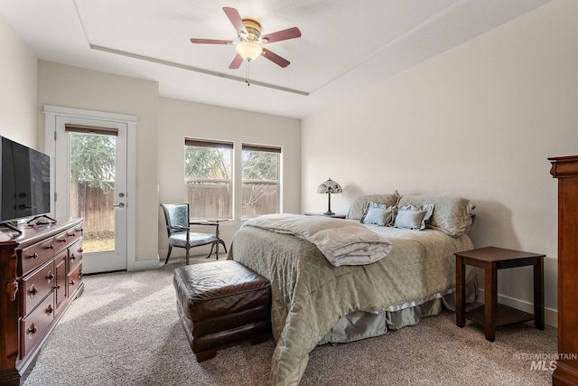 bedroom with access to exterior, a tray ceiling, light colored carpet, a ceiling fan, and baseboards