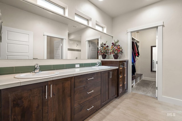 bathroom featuring double vanity, wood finished floors, a sink, and baseboards