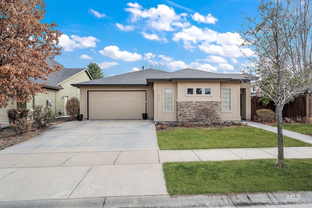 view of front facade with stucco siding, concrete driveway, fence, a garage, and a front lawn