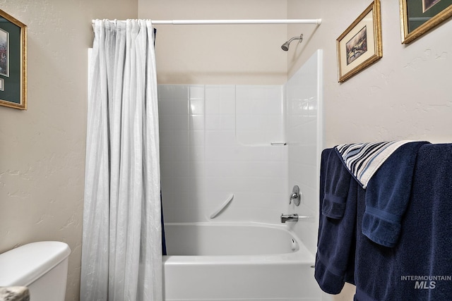 bathroom with toilet, shower / bath combo, and a textured wall