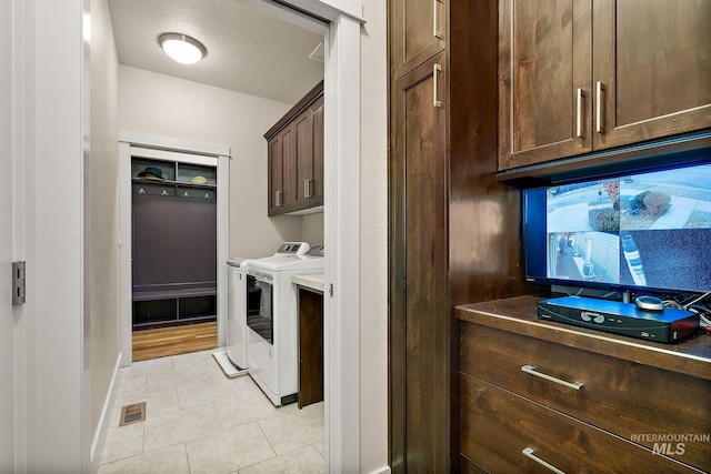 washroom featuring light tile patterned floors, cabinet space, visible vents, baseboards, and washing machine and dryer